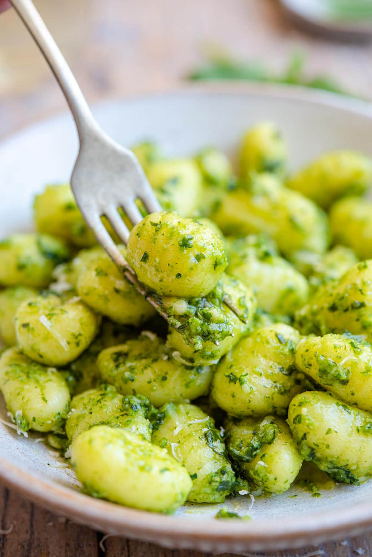 A close up of gnocchi and pesto sauce on a fork