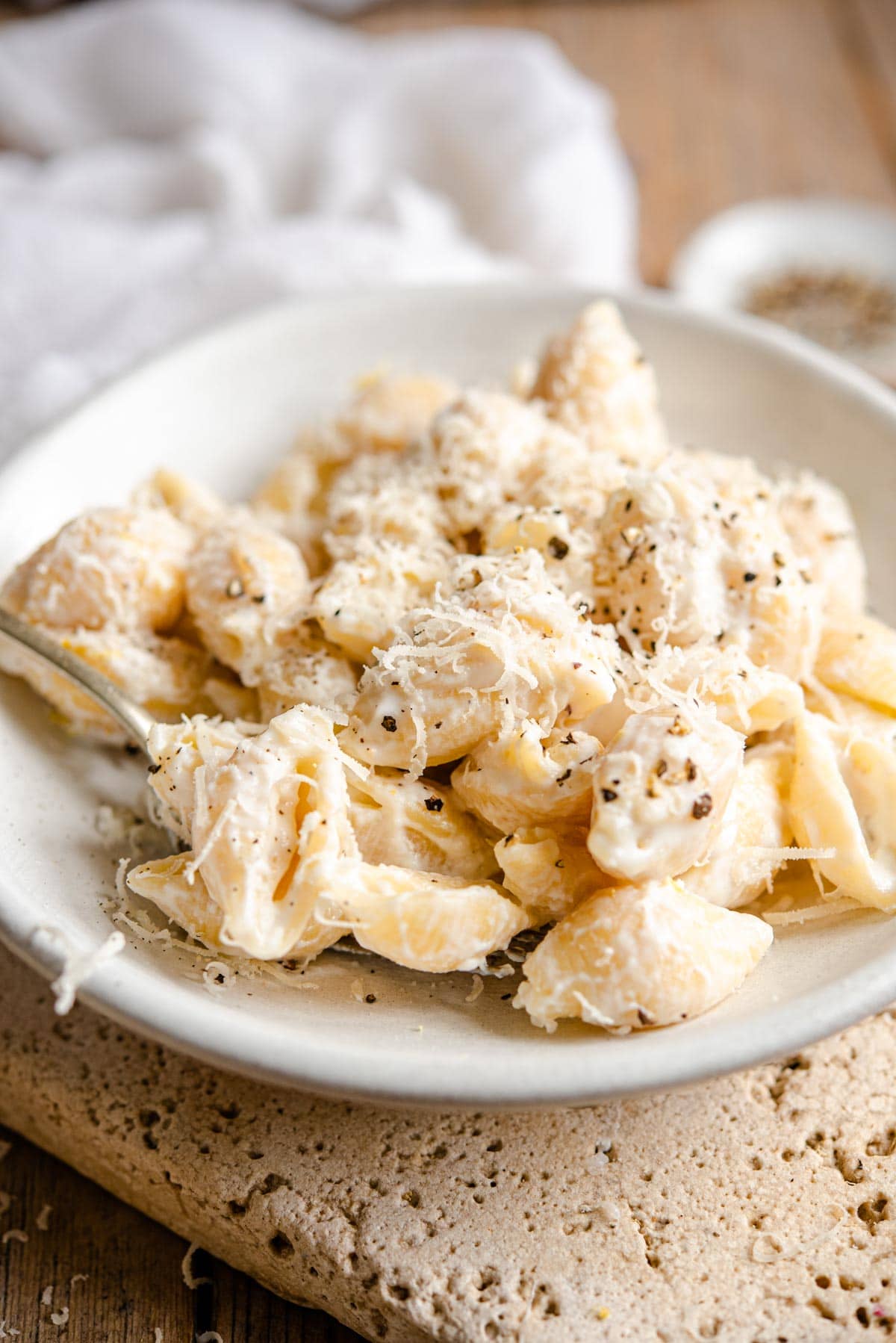 A side shot of pasta shells with a ricotta sauce in a ceramic bowl