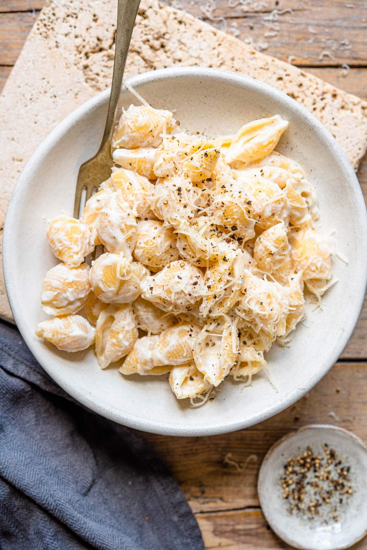 An overhead shot of ricotta pasta in a rustic bowl sitting on a wooden surface