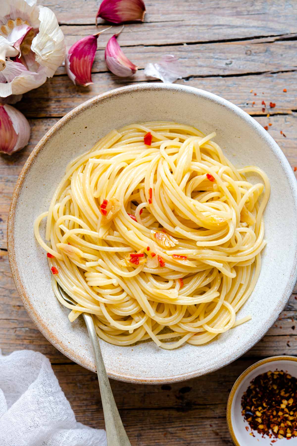 Spaghetti Aglio e Olio in a rustic bowl sitting on a wooden surface