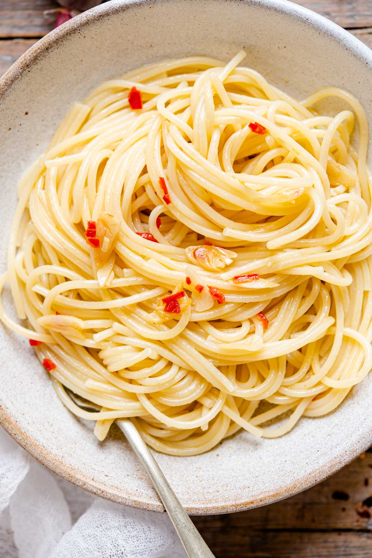 An overhead close up shot of spaghetti with garlic and oil in a bowl
