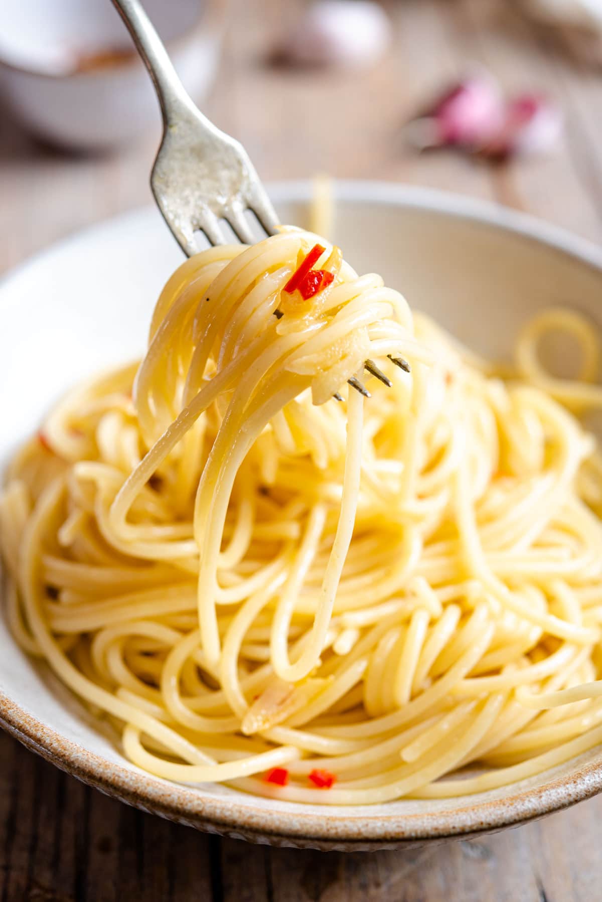 A close up of spaghetti on a fork with chlli and garlic