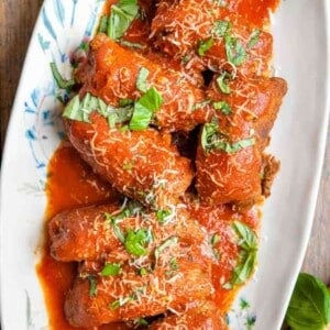 An overhead shot of beef braciole on a platter with tomato sauce