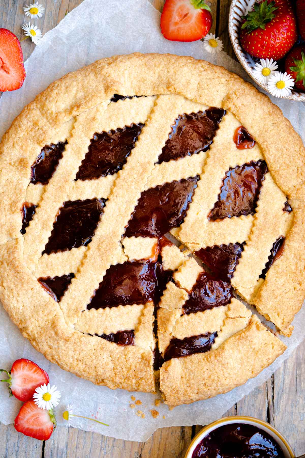 An overhead shot of a jam crostata with a slice cut