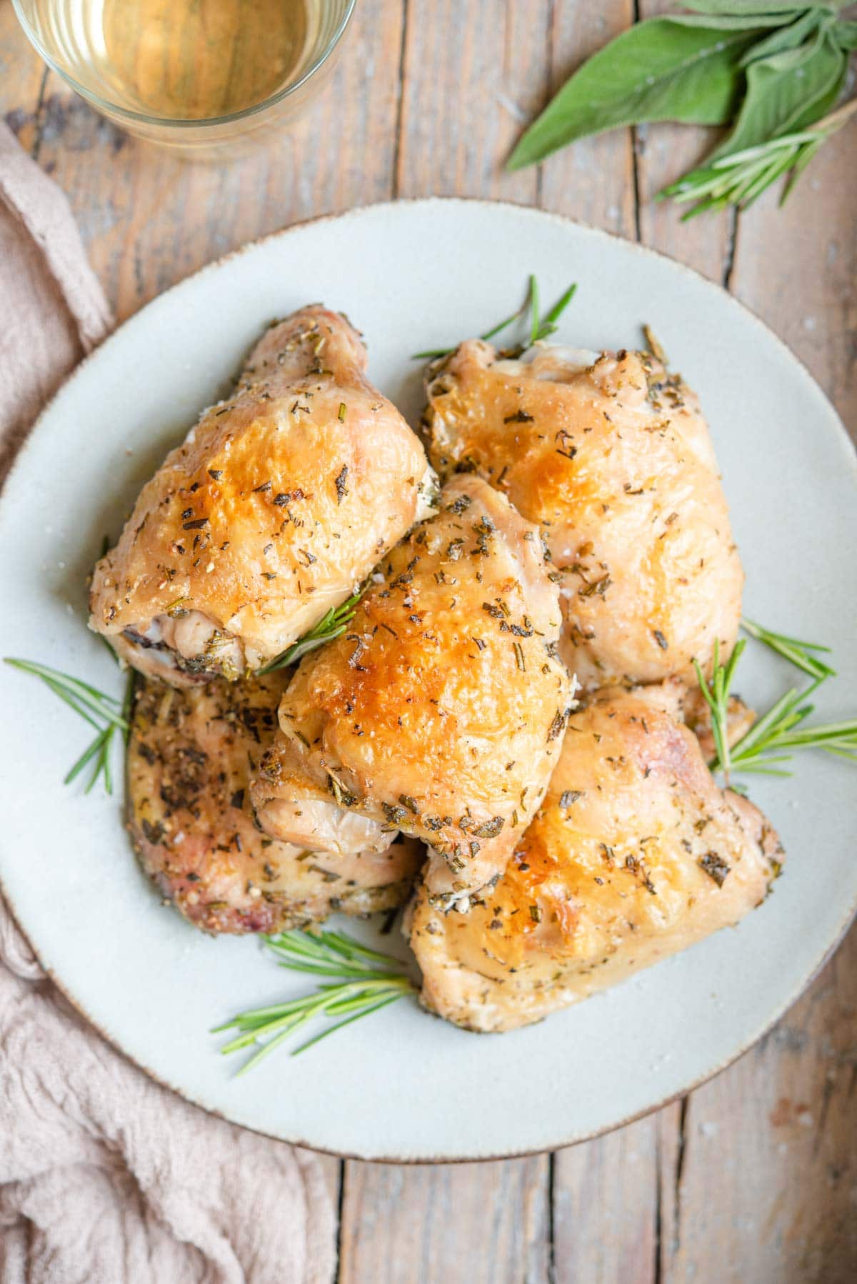 An overhead shot of Italian baked chicken thighs on a plate with rosemary