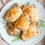 A square image of baked chicken thighs on a plate