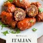Beef braciole cut open to show the cheese and herb filling on a plate with tomato sauce. Text reads: Italian Beef Braciole Sunday Dinner.