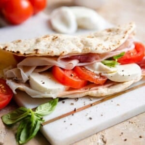 A close up of a piadina flatbread stuffed with tomatoes and mozzarella
