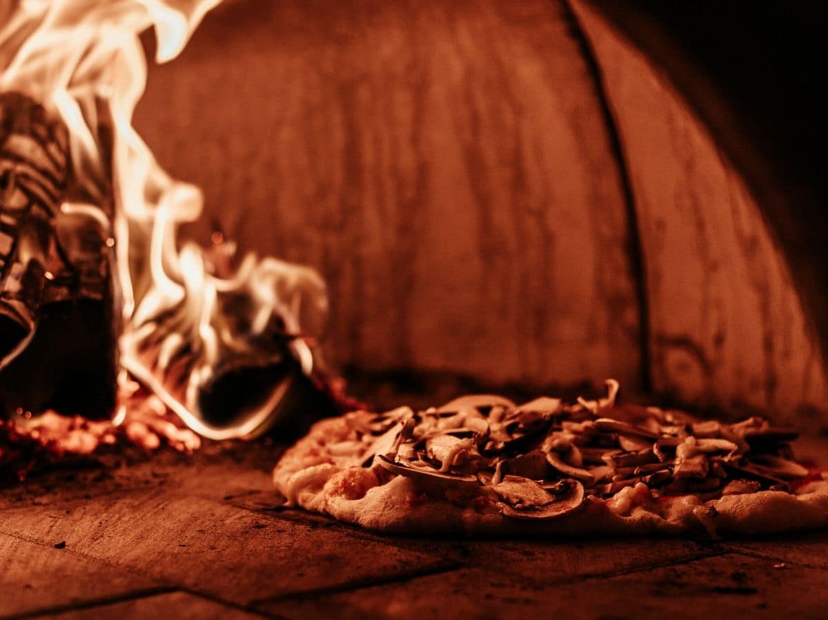 A photo of a pizza inside a wood fired pizza oven