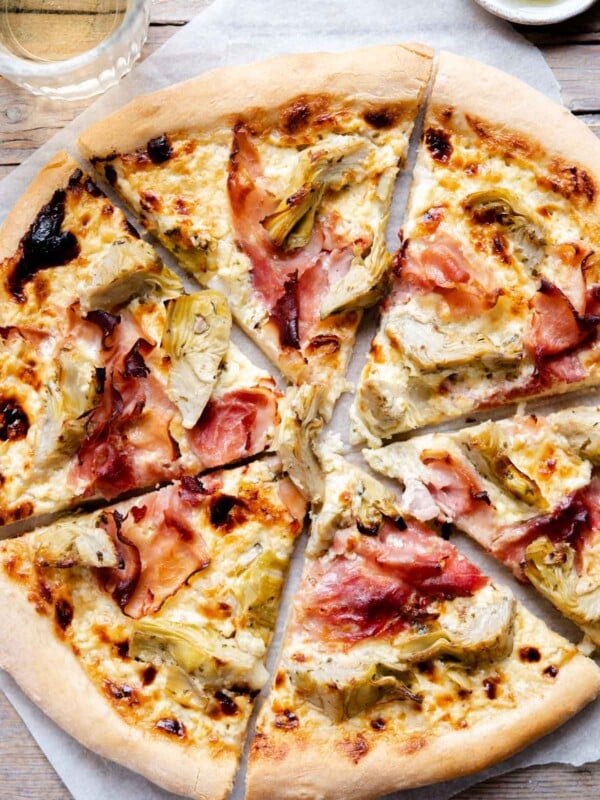 An overhead shot of an artichoke pizza cut into slices