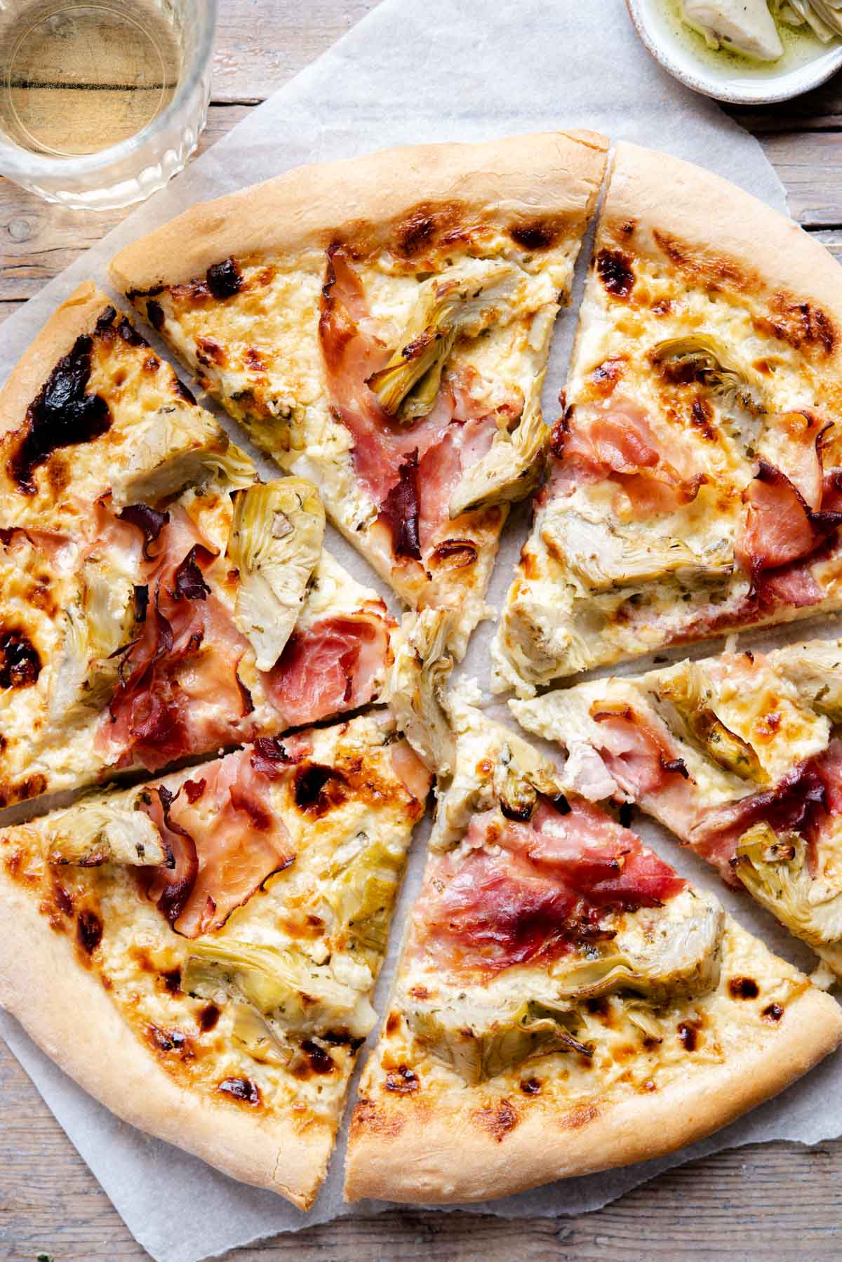 An overhead shot of an artichoke pizza cut into slices