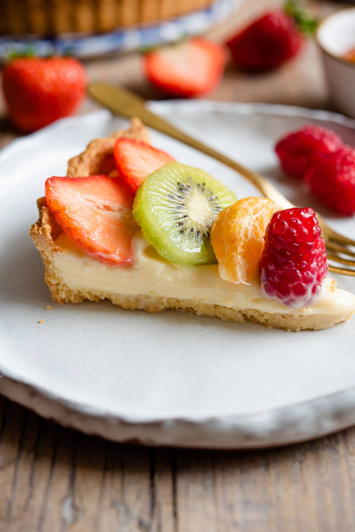 A slice of tart filled with pastry cream and fresh fruit