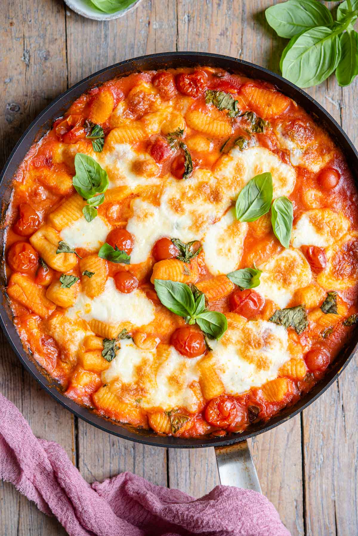 An overhead shot of gnocchi alla sorrentina in a skillet sitting on a wooden surface