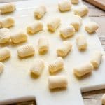 A side shot of potato gnocchi on a white marble cutting board