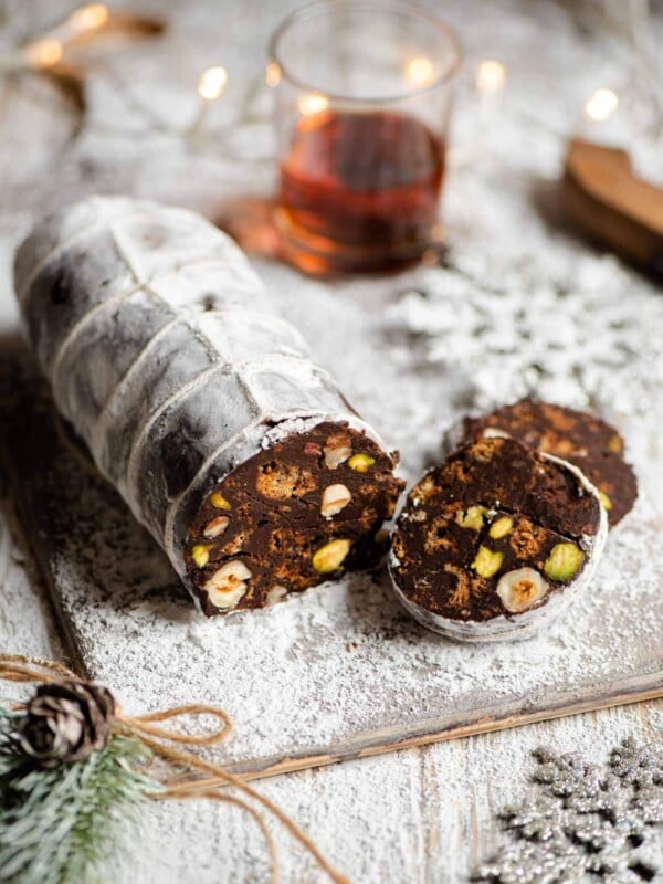 A chocolate salami on a white board with slices cut