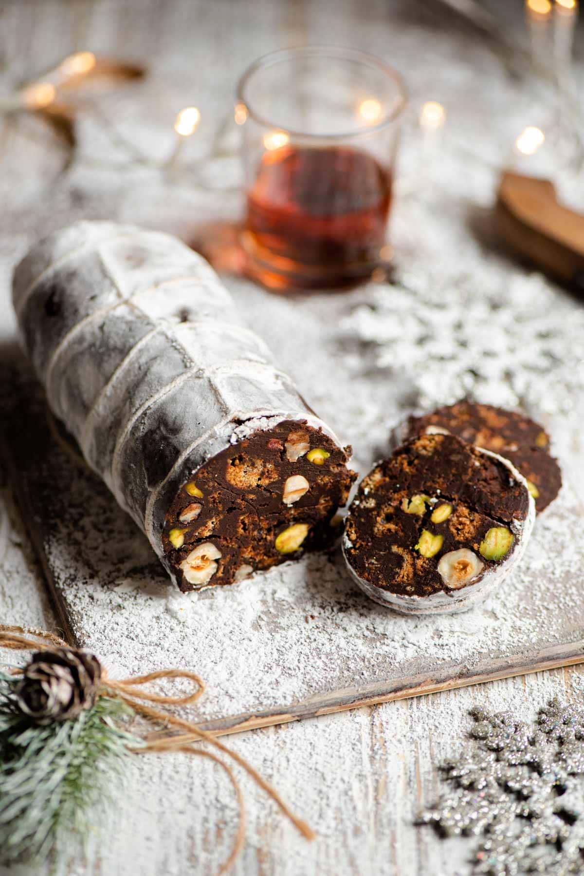 A chocolate salami on a wooden board with a few slices cut from it