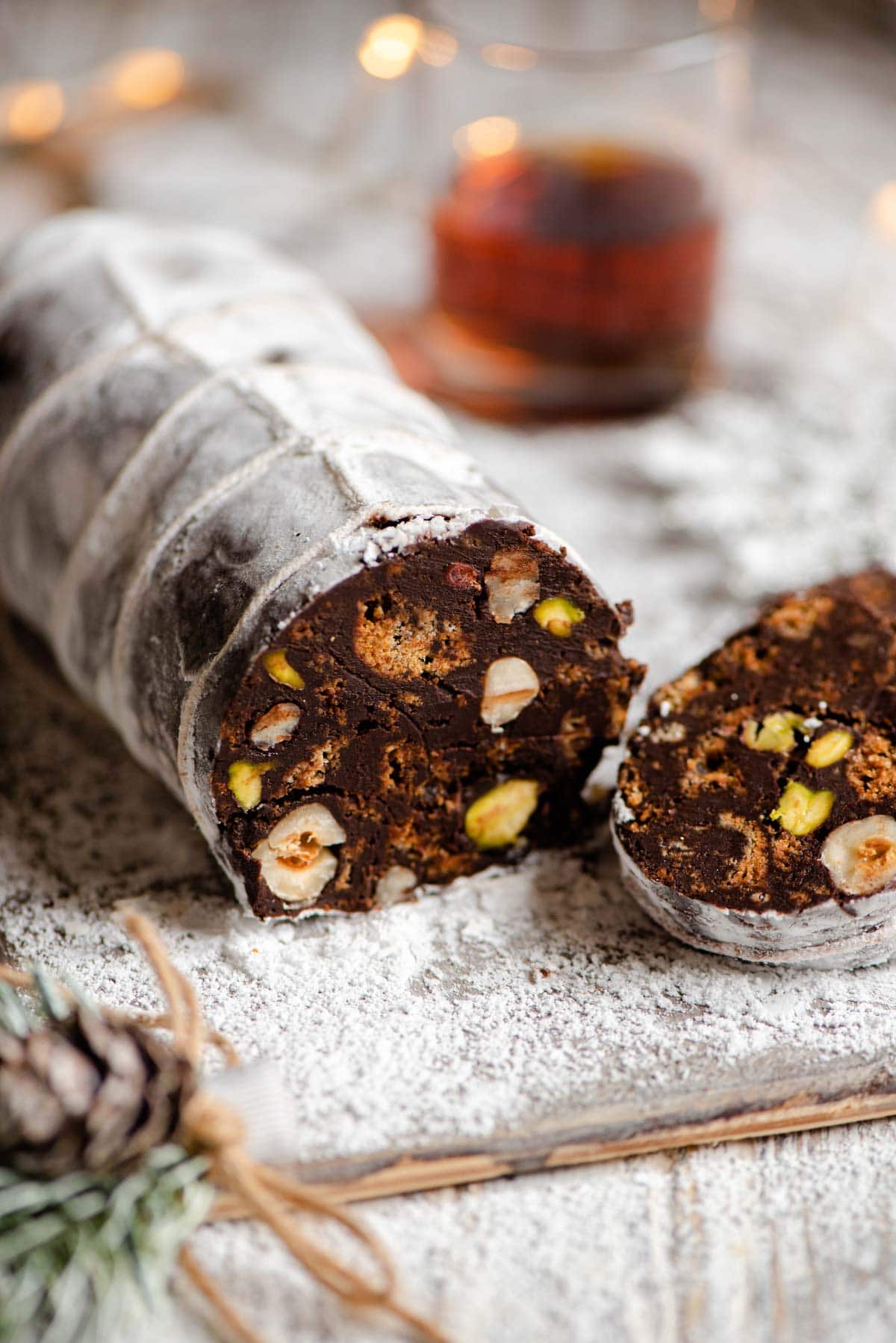 A close up of chocolate salami cut open showing the nuts and cookies inside