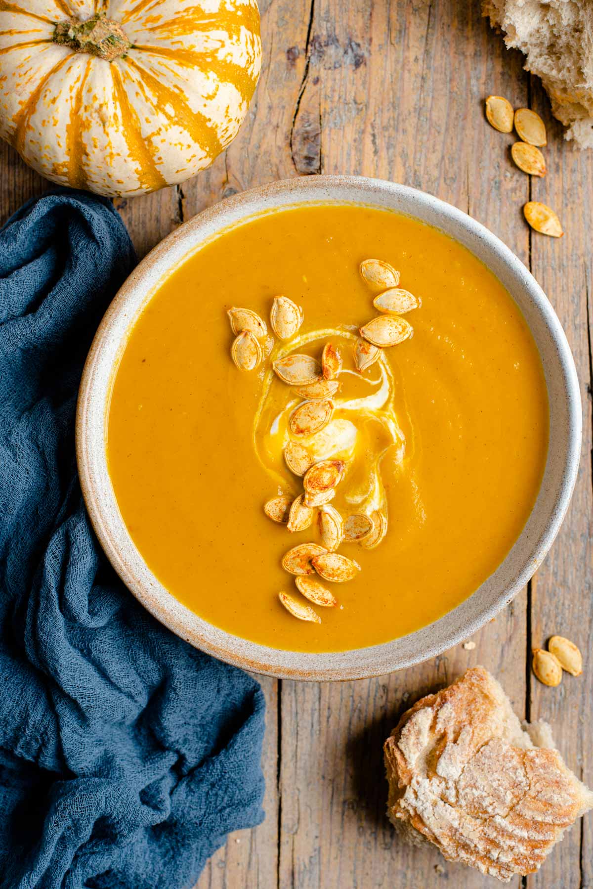 An overhead shot of a bowl of pumpkin soup topped with toasted pumpkin seeds