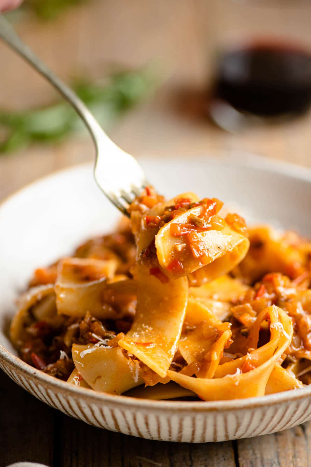 A close up of a forkful of pasta with vegetable sauce