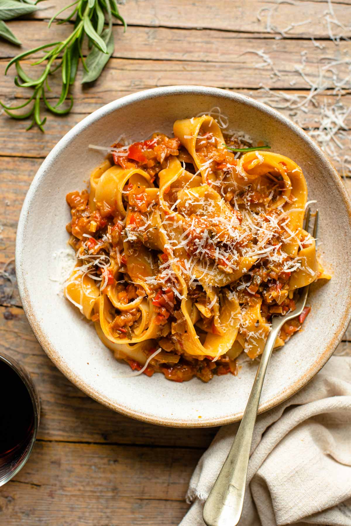 An overhead shot of a bowl of pasta with a vegetable sauce topped with parmesan cheese