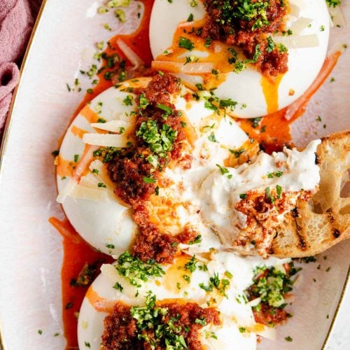 An overhead shot of burrata cheese on a serving plate with nduja and gremolata
