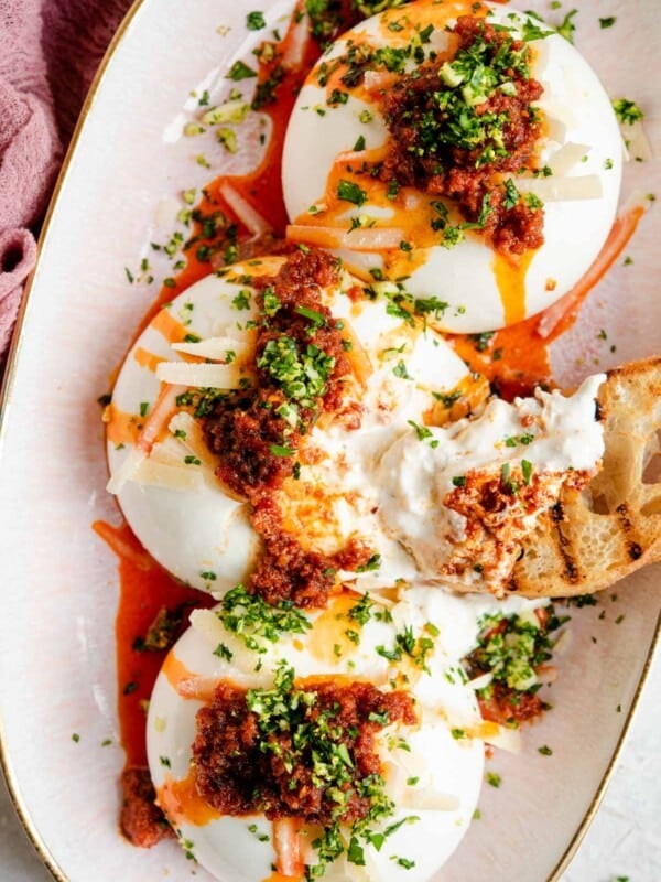 An overhead shot of burrata cheese on a serving plate with nduja and gremolata