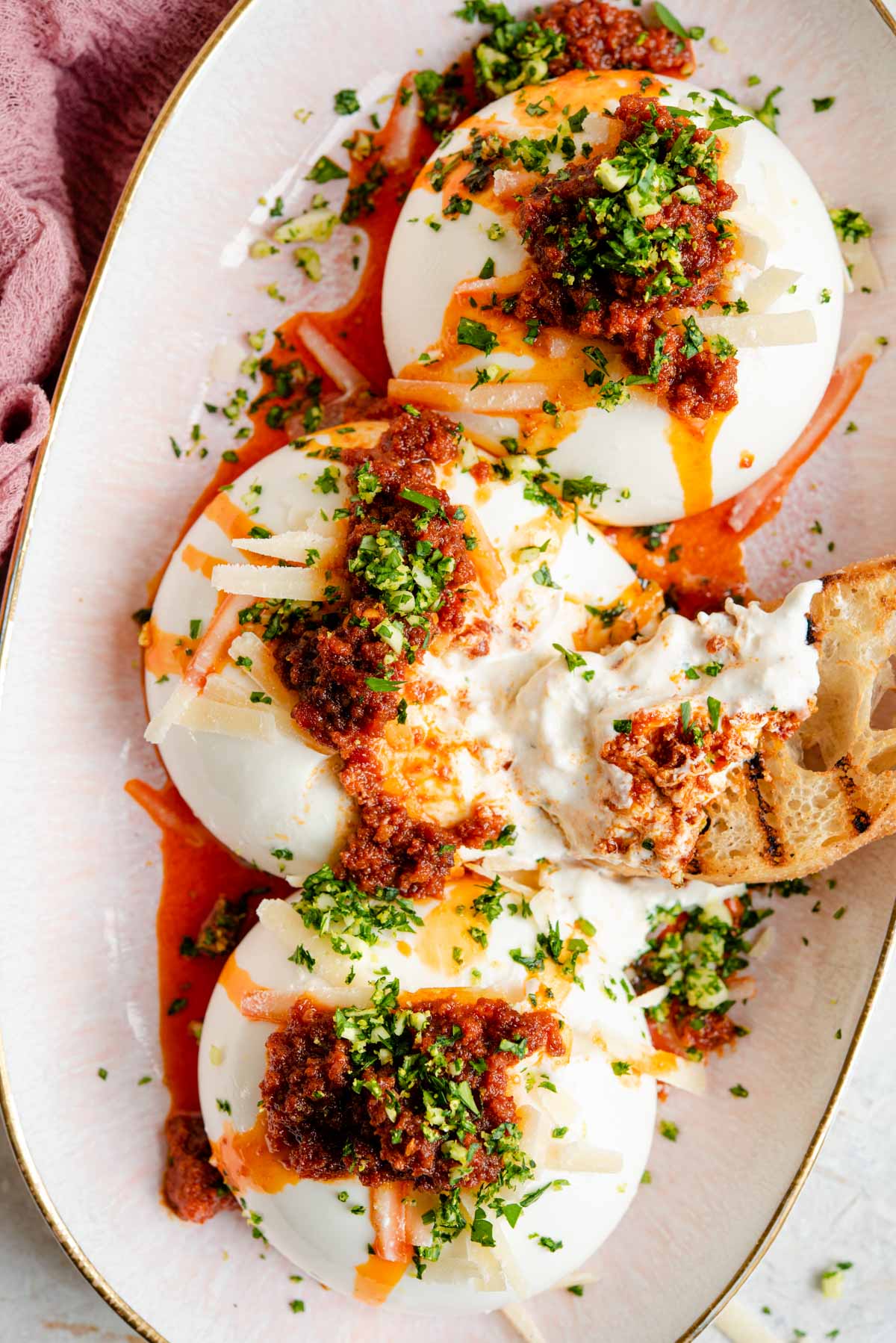 An overhead shot of burrata cheese on a serving plate with nduja and gremolata