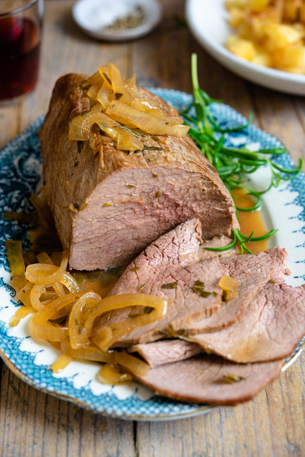 Italian roast beef on a platter with slices cut, marsala sauce and onions