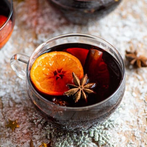 A mug of muled wine on a snowy wooden surface