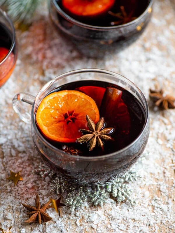 A mug of muled wine on a snowy wooden surface