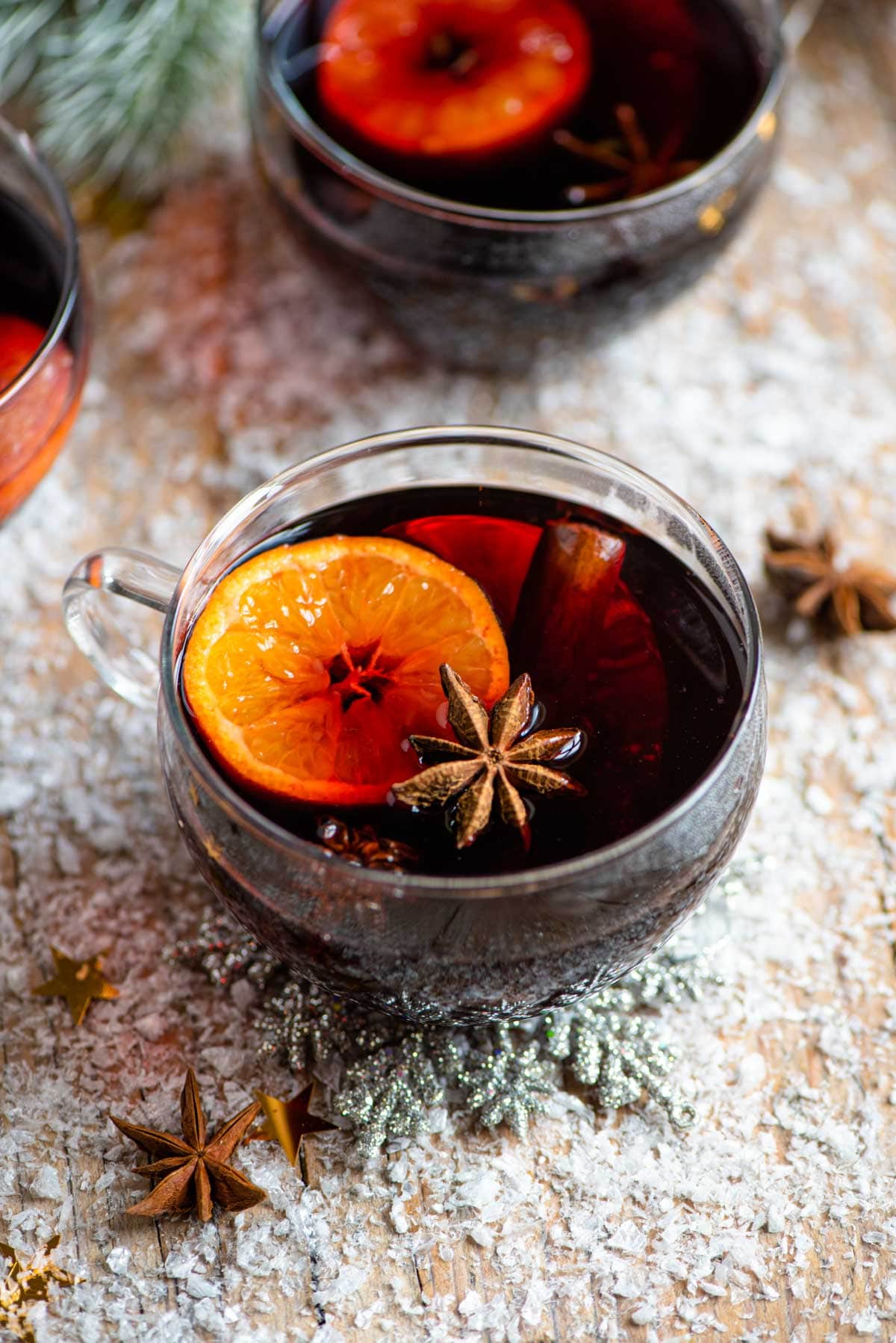 A mug of muled wine on a snowy wooden surface