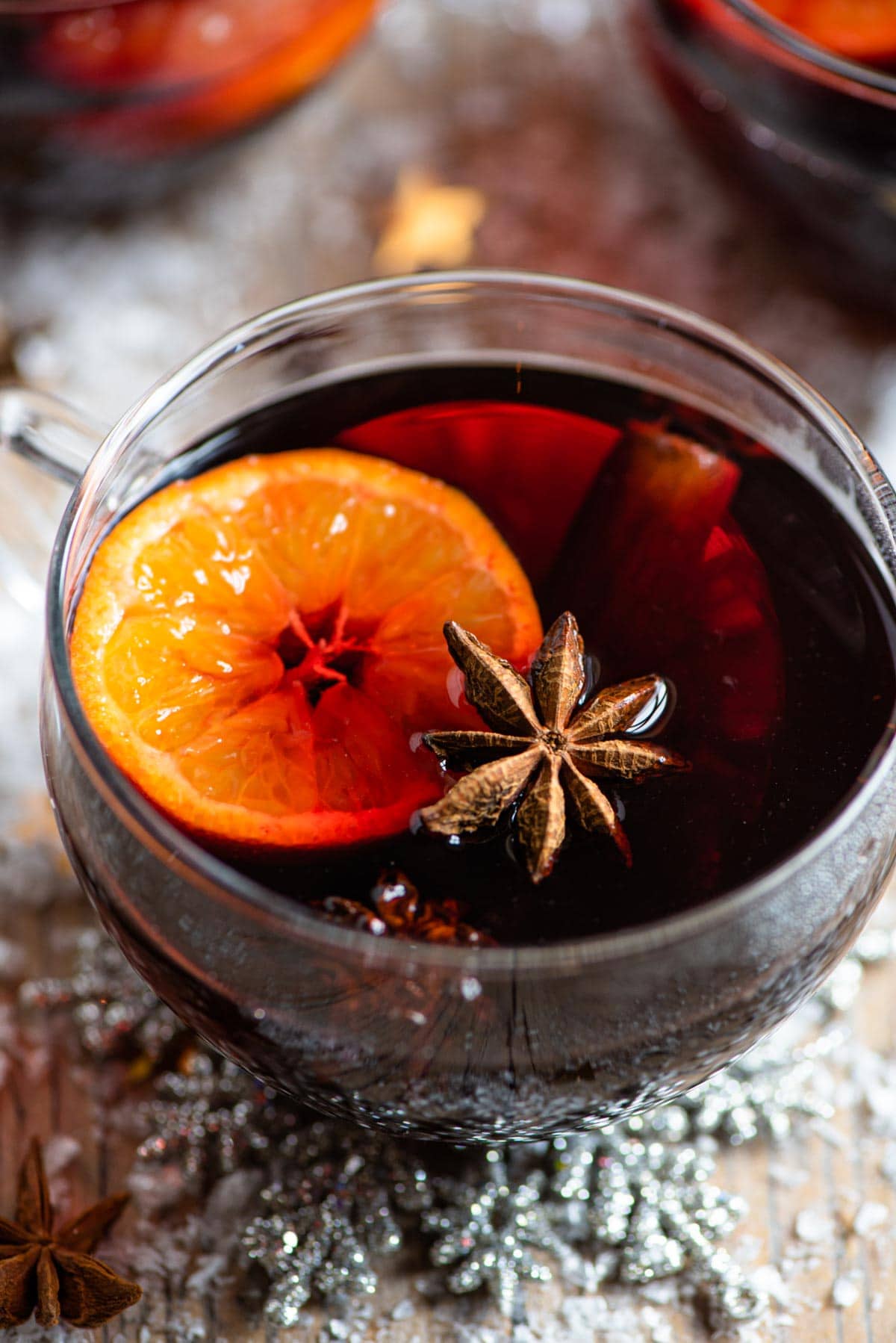 A close up of a mug of mulled wine with oranges, star anise and cinnamon