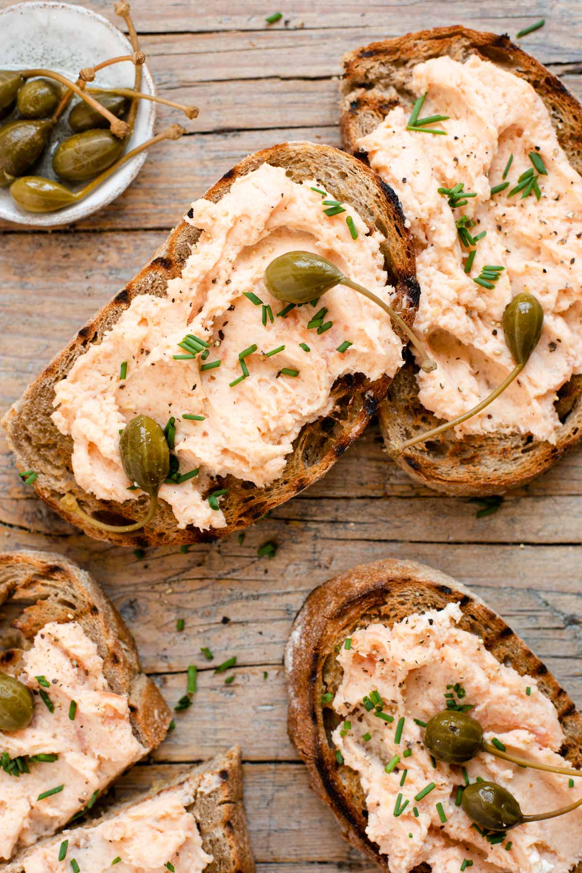 An overhead shot of smoked salmon crostini on a wooden surface