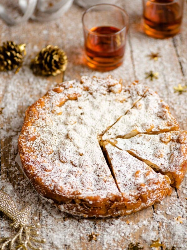 Panforte on a wooden table cut into slices with christmas decorations around