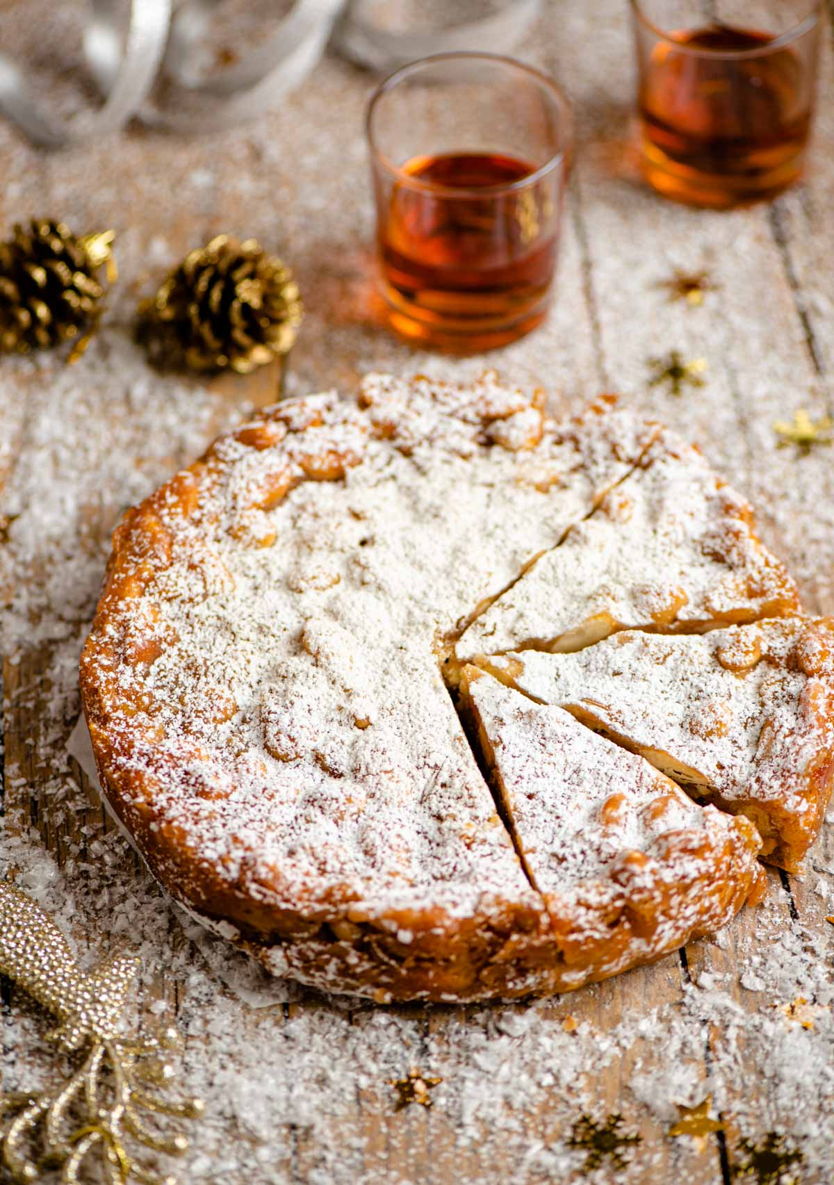 Panforte on a wooden table cut into slices with christmas decorations around