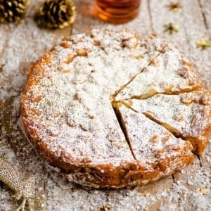 A close up of panforte on a wooden board dusted with powdered sugar