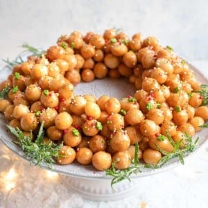 Struffoli honey balls in a ring shape on a cake stand covered in sprinkles