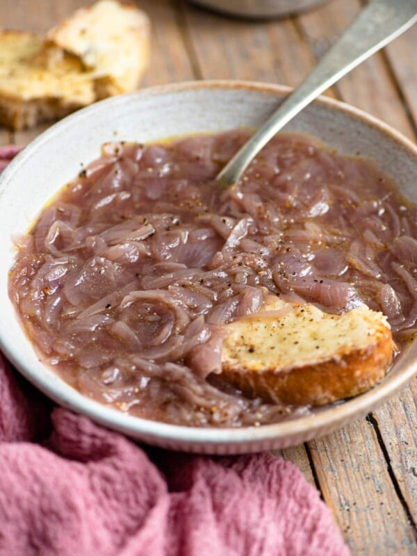 A bowl of Carabaccia onion soup with a piece of cheesy bread at the side