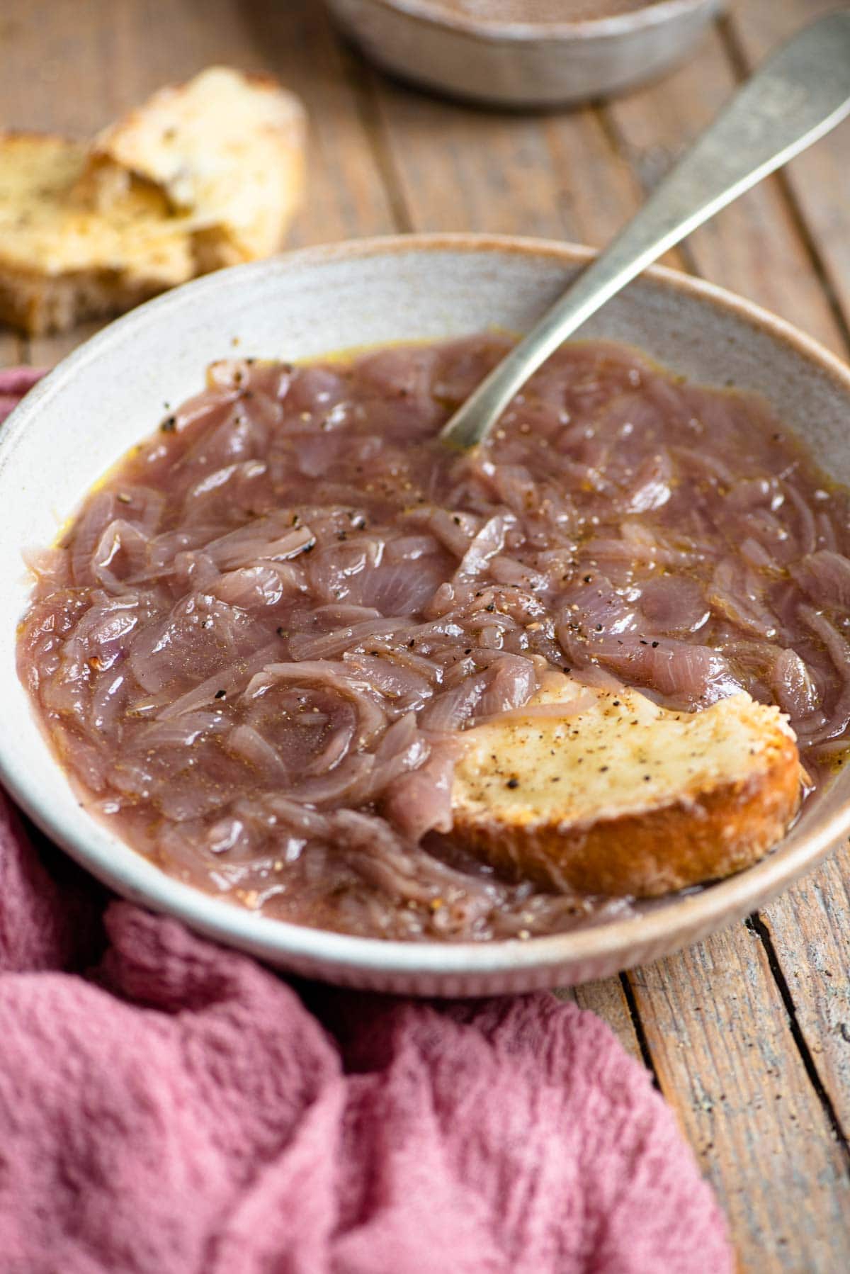 A bowl of Carabaccia onion soup with a piece of cheesy bread at the side