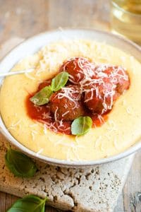 Eggplant meatballs in tomato sauce sitting on top of a bowl of polenta
