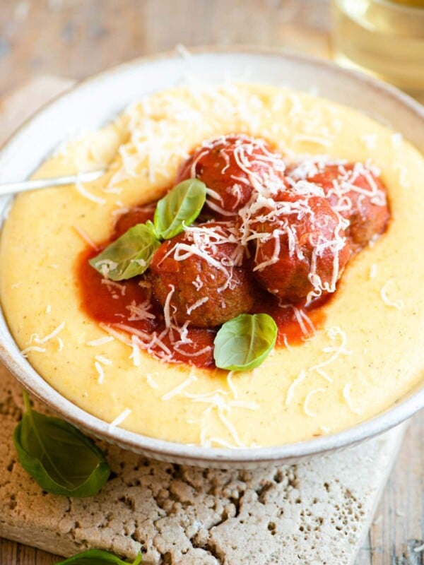 Eggplant meatballs in tomato sauce sitting on top of a bowl of polenta