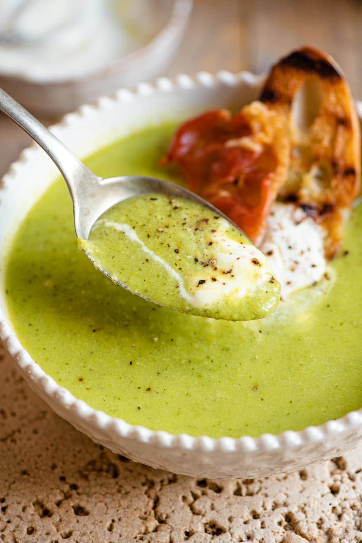 A close up of a spoonful of green pea soup