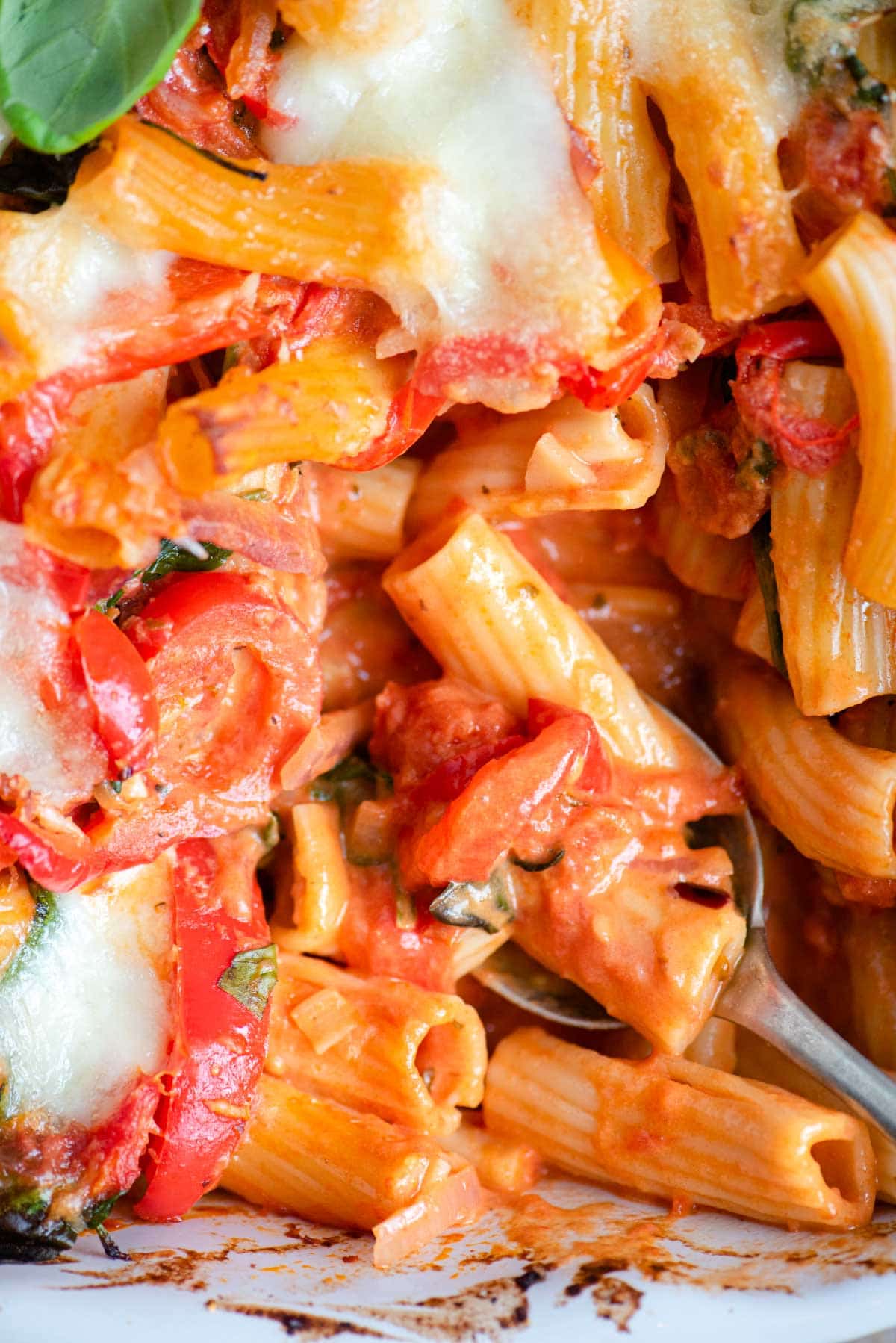 A close up of baked ziti with vegetables in a tomato sauce