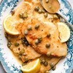 A close up of chicken piccata on a blue plate