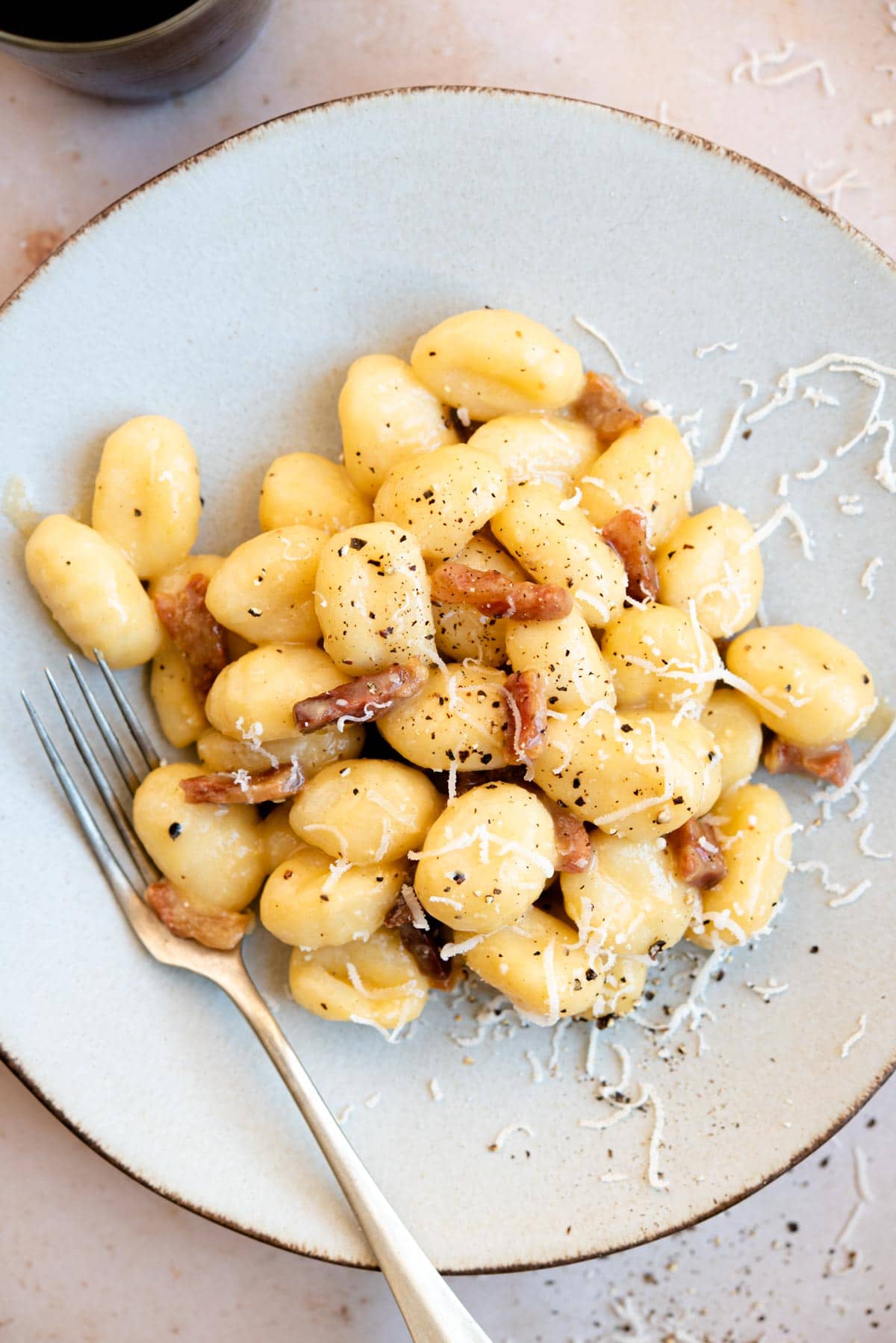 An overhead shot of a plate of gnocchi with carbonara sauce