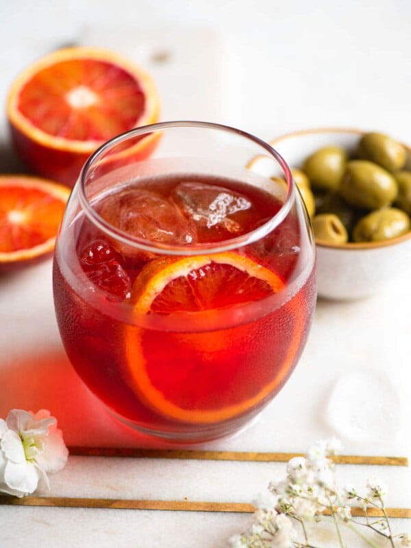 A close up of a Negroni Sbagliato cocktail with olives at the side