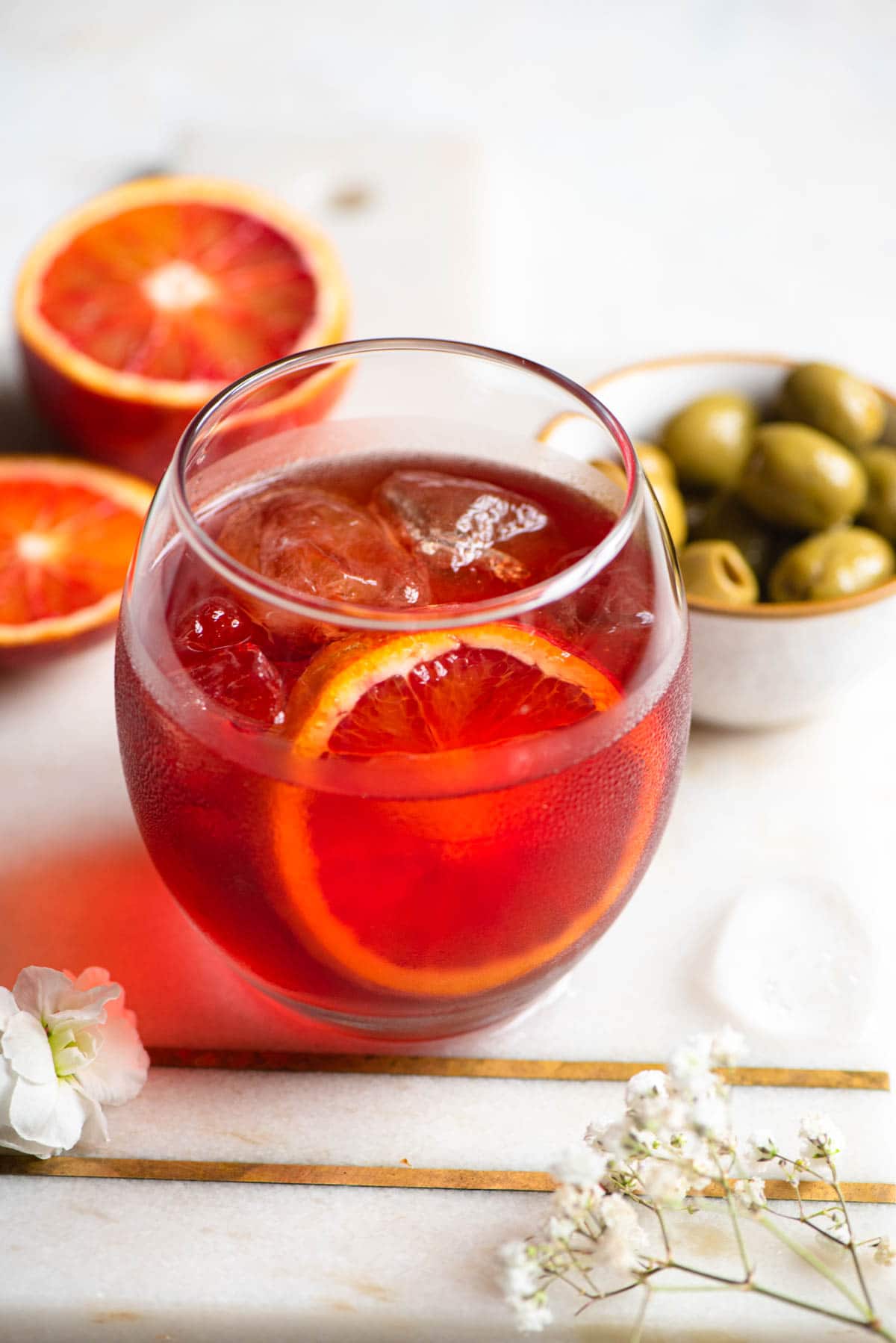 A close up of a Negroni Sbagliato cocktail with olives at the side
