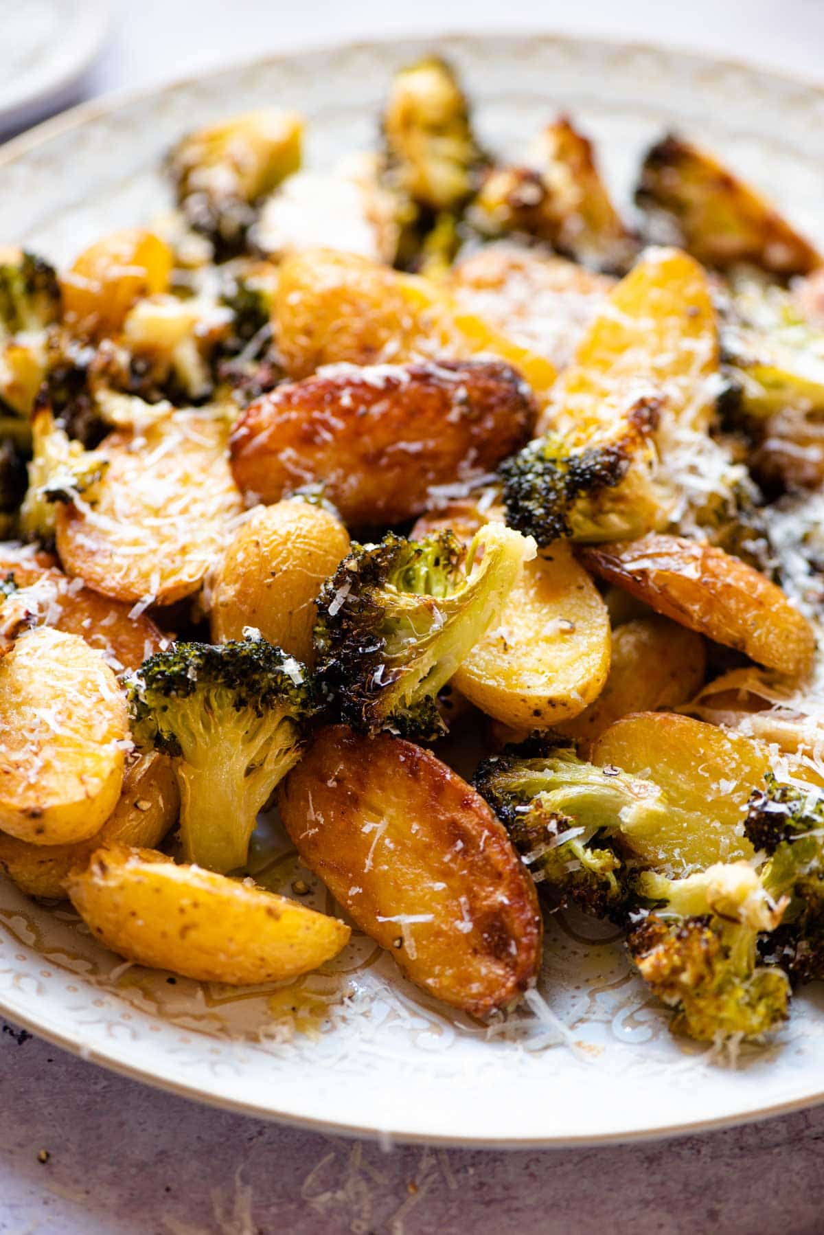 A close up of roasted potatoes and broccoli with parmesan