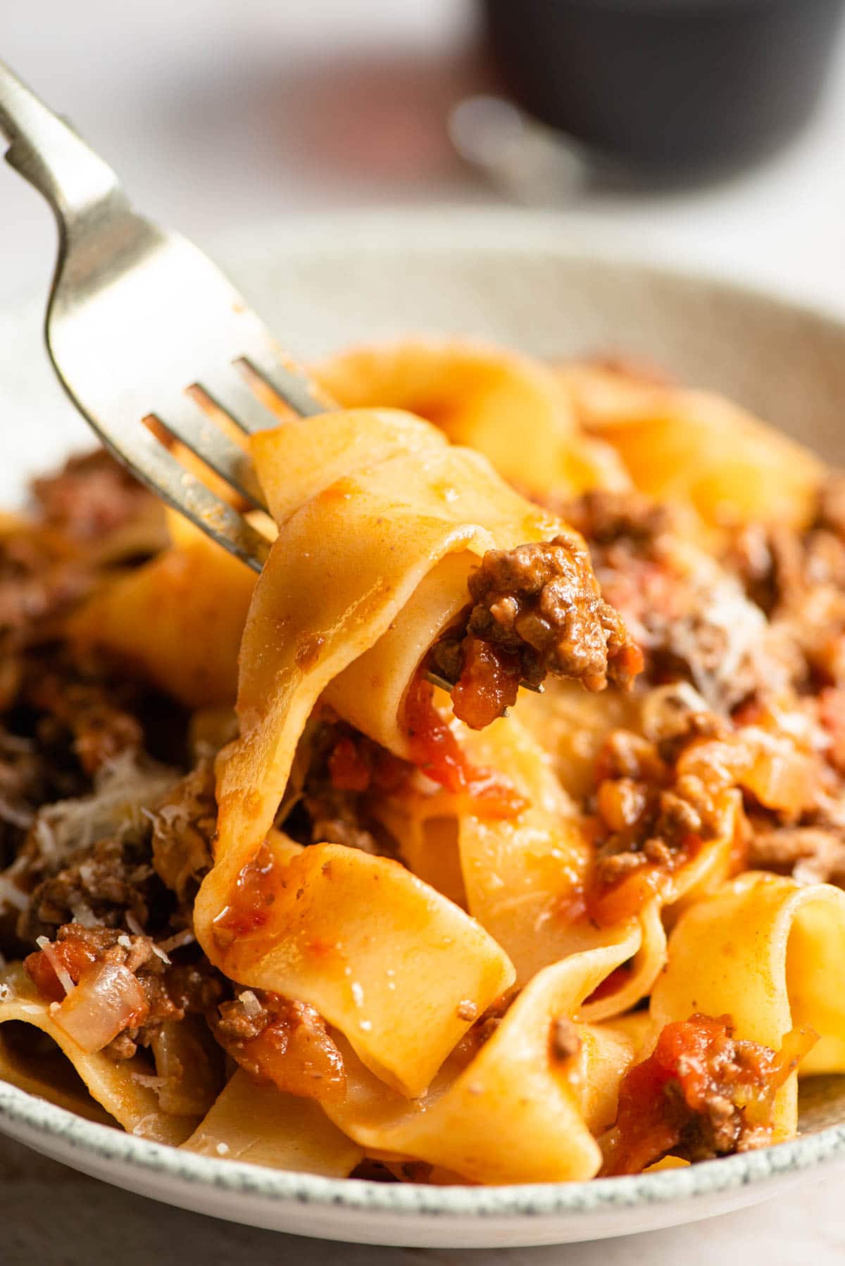 A close up of lamb ragu and pappardelle pasta on a fork