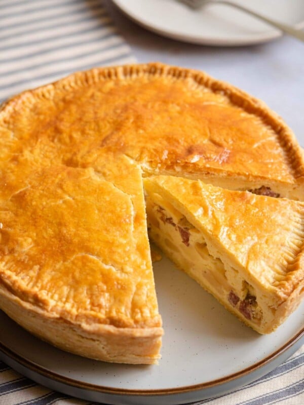 Pizza Rustica on a serving plate with a slice cut